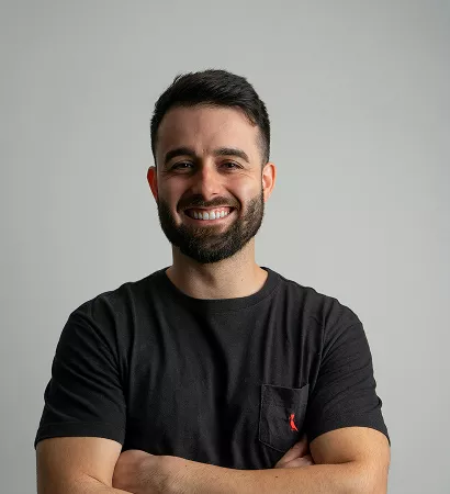 A man with a beard wearing a black shirt, looking directly at the camera with a neutral expression