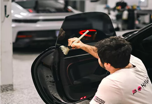 A man is cleaning the door of a car with a cloth, focusing on removing dirt and smudges
